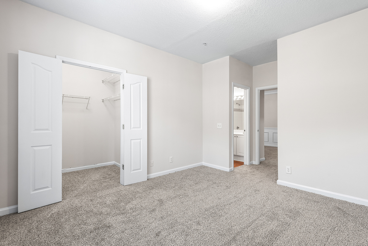 Inviting bedroom with plush carpeting, spacious walk-in closet, and bright natural light for a cozy atmosphere.