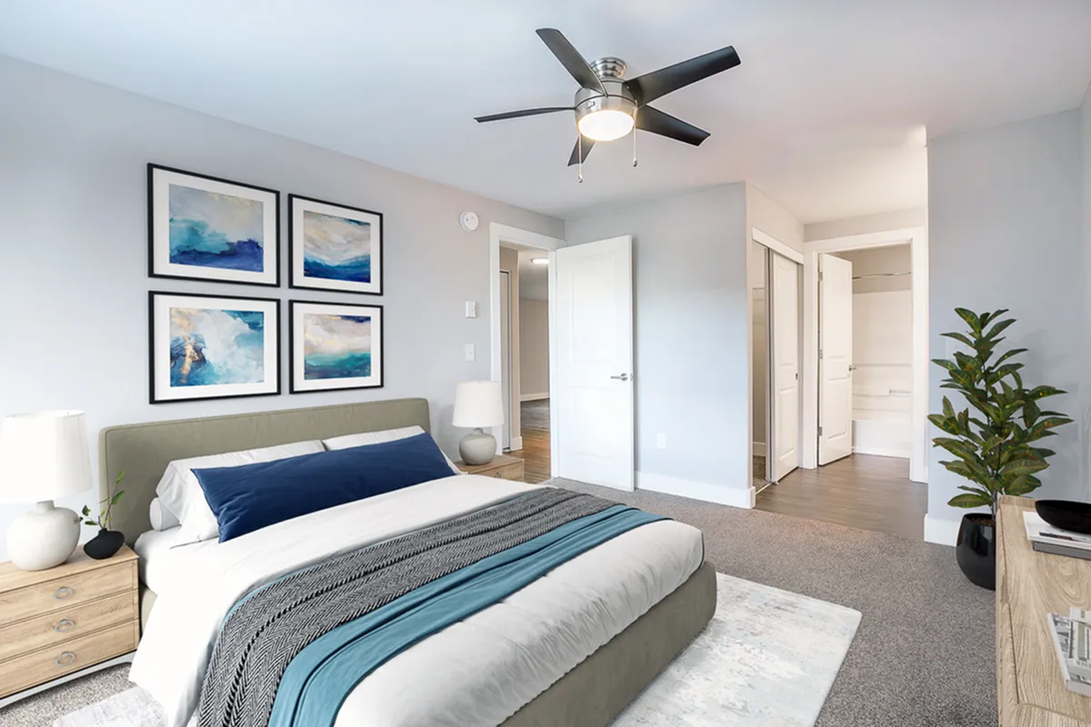 Inviting bedroom with modern decor, featuring a plush bed, stylish ceiling fan, and serene abstract artwork.