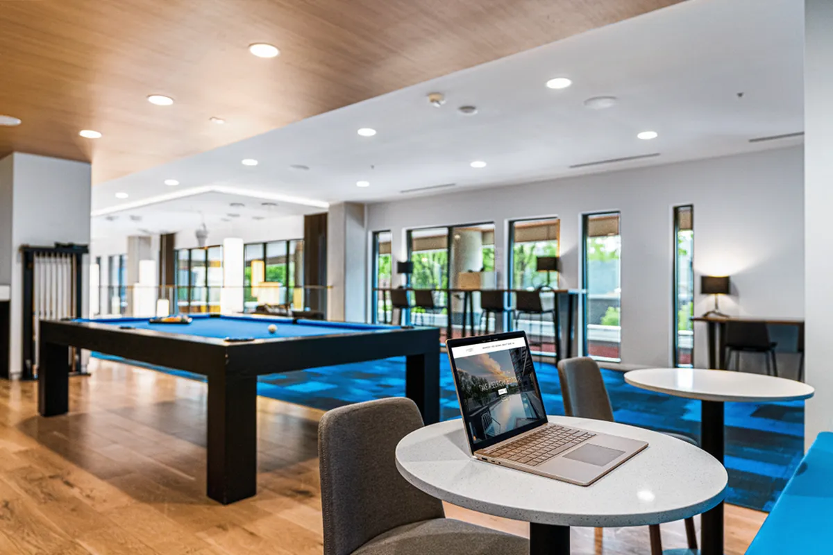 Chic modern lounge with a sleek pool table, stylish bar seating, and laptop-friendly tables, perfect for relaxation and entertainment at Apt CoWork at Sugarmont Apartments in Sugarhouse UT