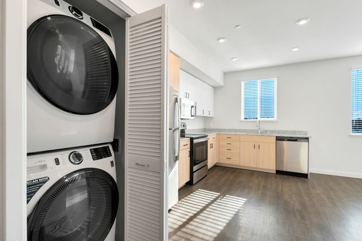 Modern kitchen with sleek appliances and laundry area featuring a stylish washer and dryer combo, perfect for contemporary living at 805 Riverfront Apartments in West Sacramento