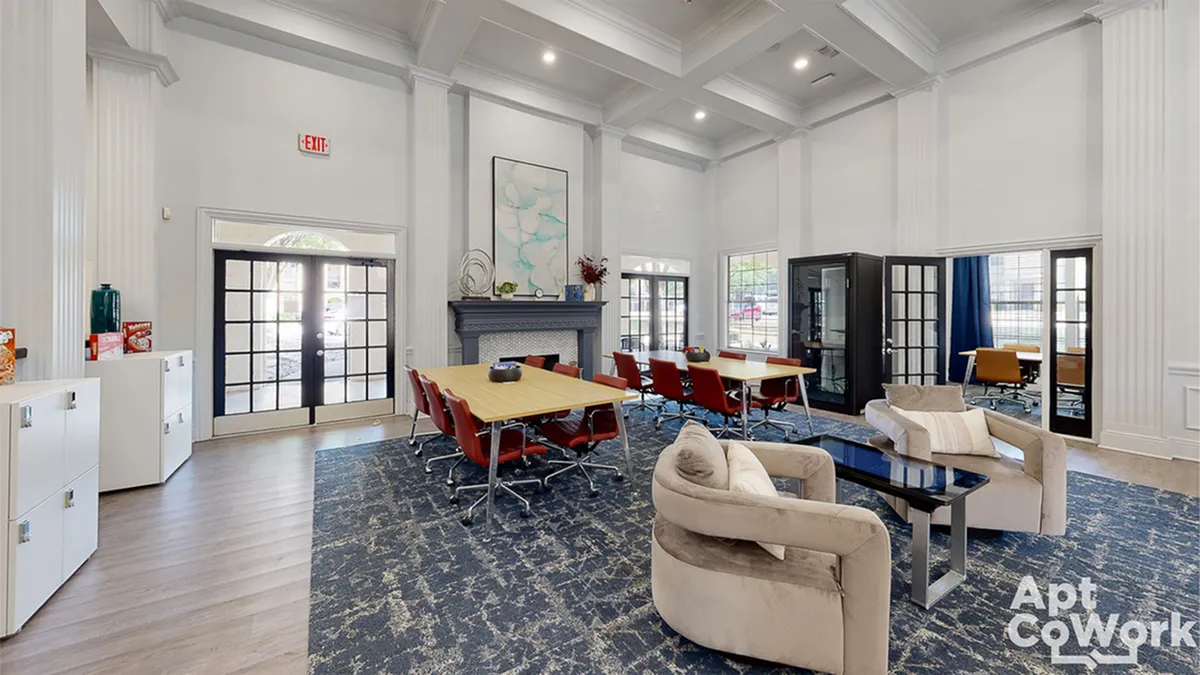 Inviting co-working space with high ceilings, stylish modern decor, and ample natural light, featuring comfortable seating and spacious meeting tables.