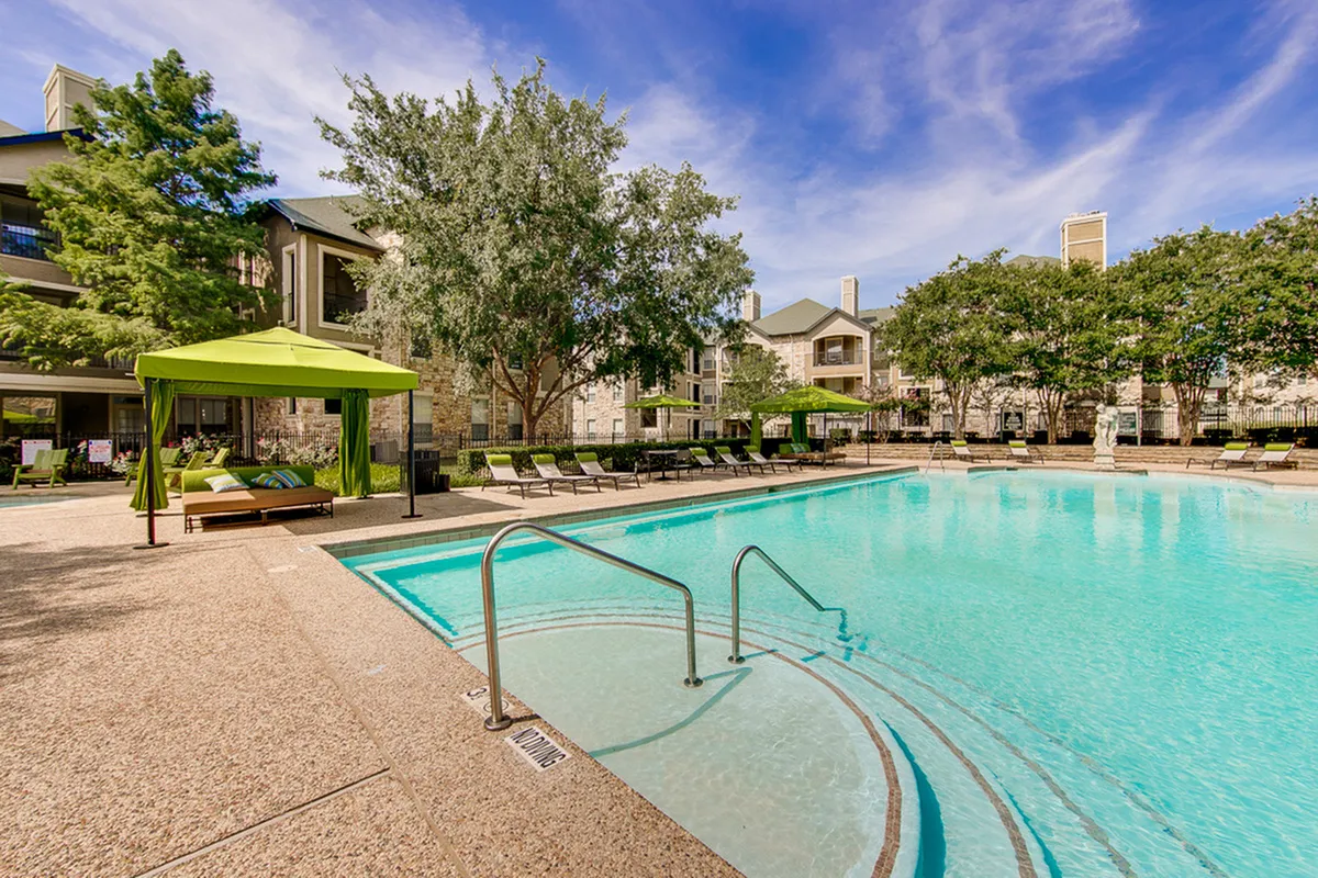 Inviting outdoor pool area with elegant sun loungers, vibrant green cabanas, and lush landscaping, perfect for relaxation and leisure.
