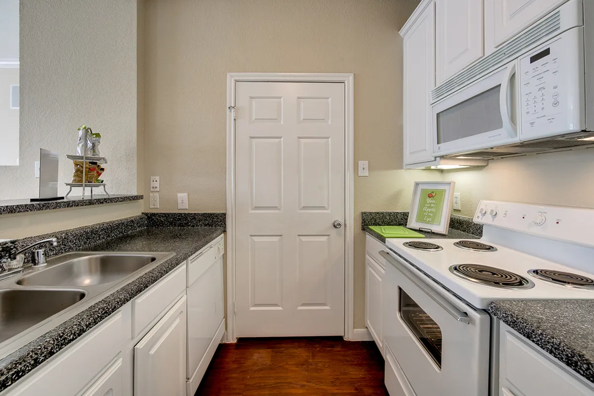 Bright kitchen with sleek granite countertops, white cabinetry, and modern appliances, perfect for culinary adventures.