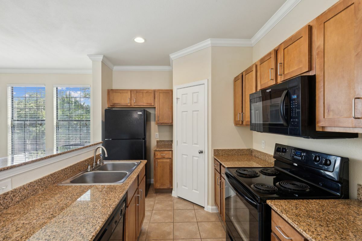 Elegant kitchen with modern appliances, granite countertops, and natural light streaming through large windows at Enclave on Golden Triangle in Fort Worth Tx