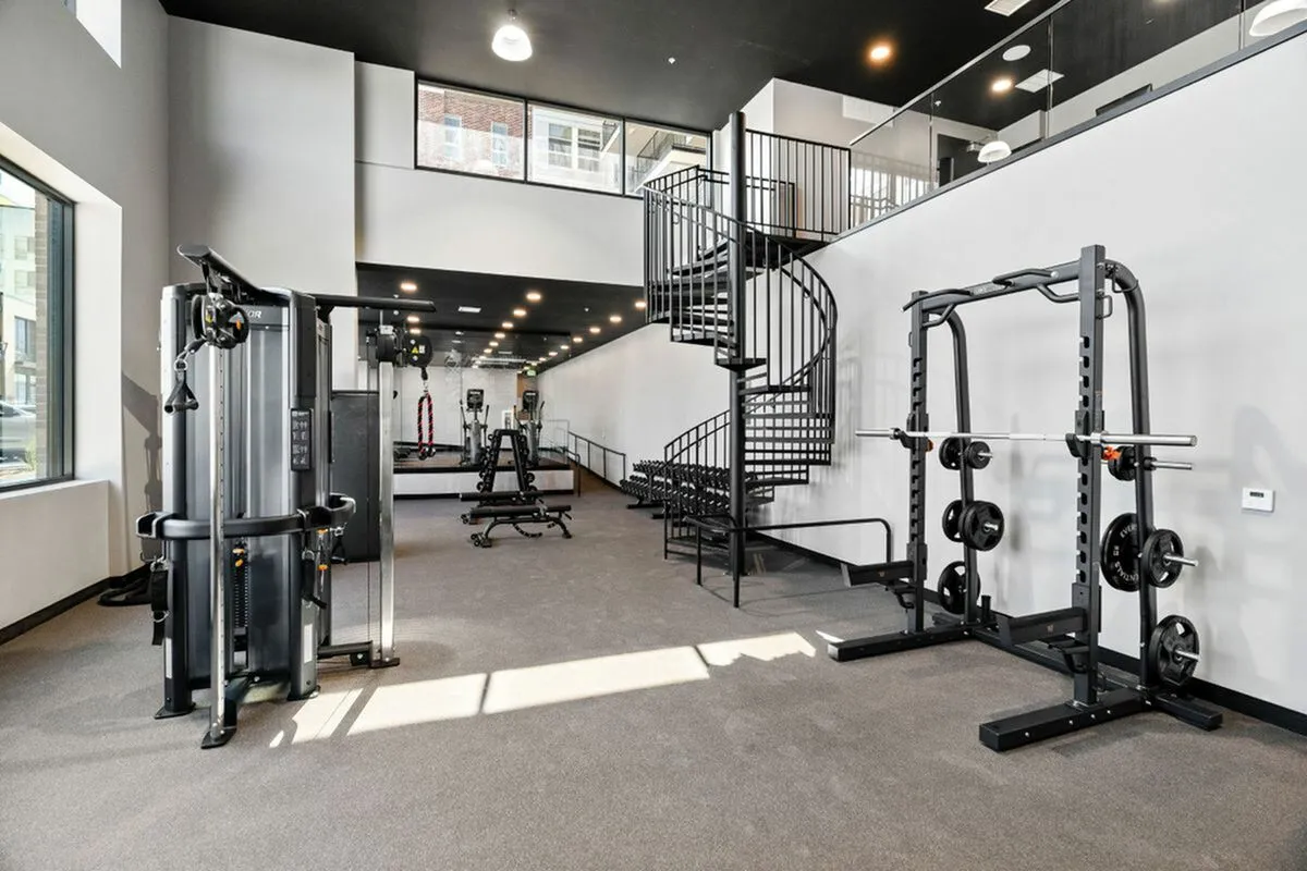 Modern fitness center at The Richmond featuring state-of-the-art gym equipment and sleek spiral staircase in a bright, airy space.