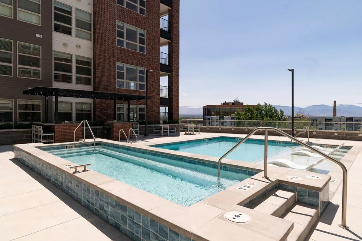 Luxurious apartment pool and spa area with modern design, featuring pristine swimming lanes, relaxing lounge chairs, and a scenic mountain view at The Richmond Apartments in SLC