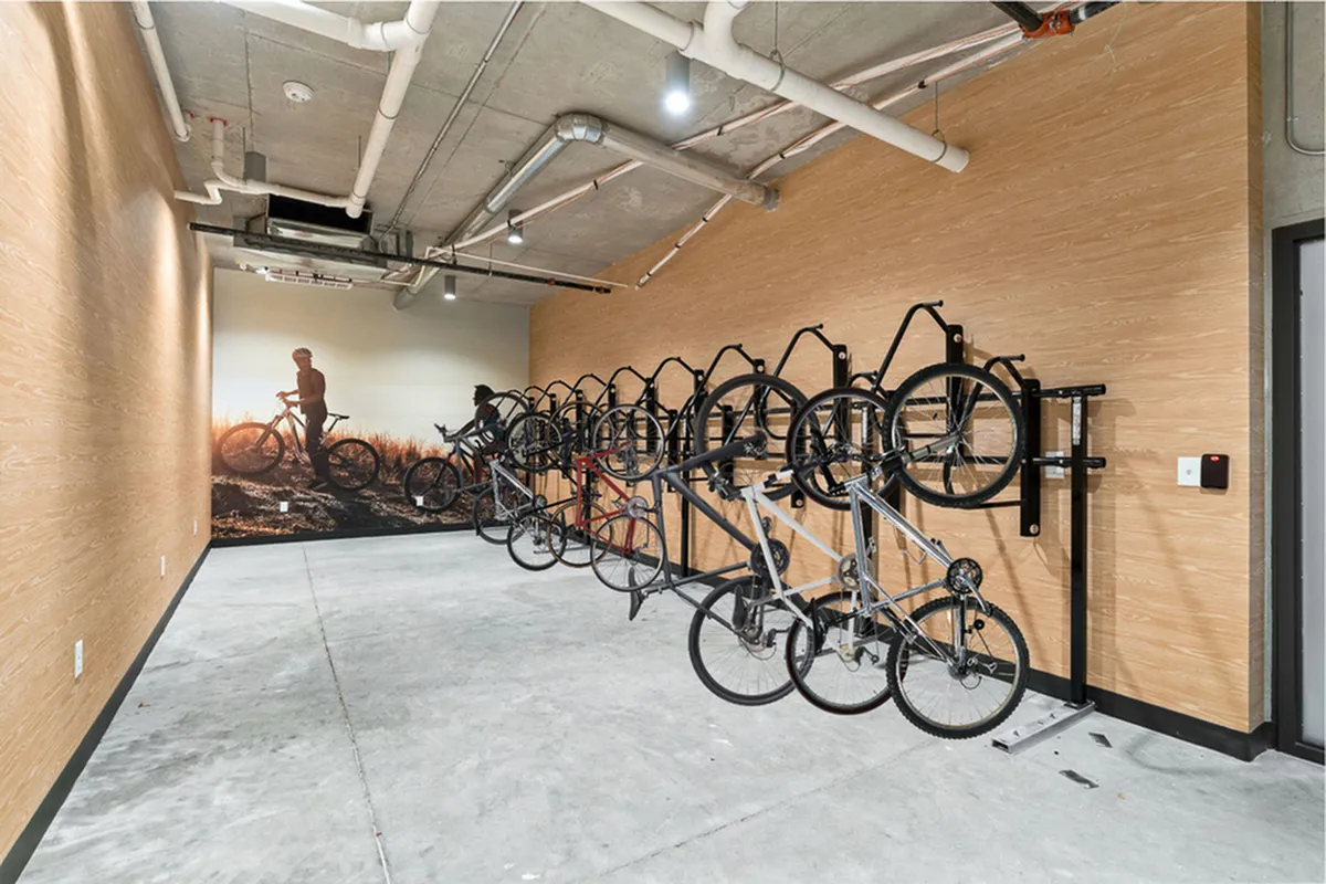 Modern apartment bike storage room with wall-mounted racks and nature-themed mural, ideal for cycling enthusiasts at The Richmond Apartments in Millcreek Utah