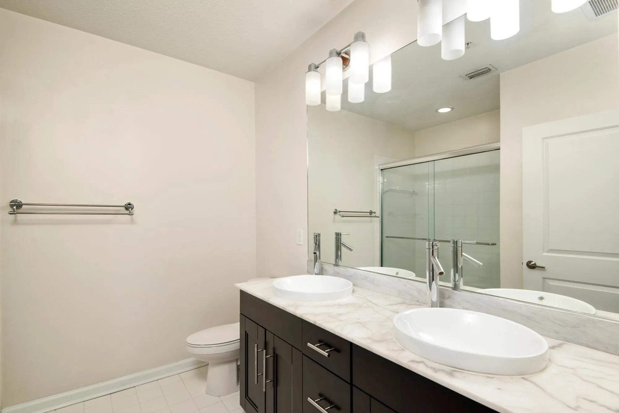 Elegant bathroom featuring a dual-sink vanity with a sleek marble countertop and modern lighting, perfect for a luxurious living space.