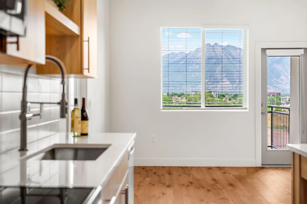 Bright modern kitchen with sleek countertops, stylish faucet, and scenic mountain view through large window, enhancing the elegant atmosphere.