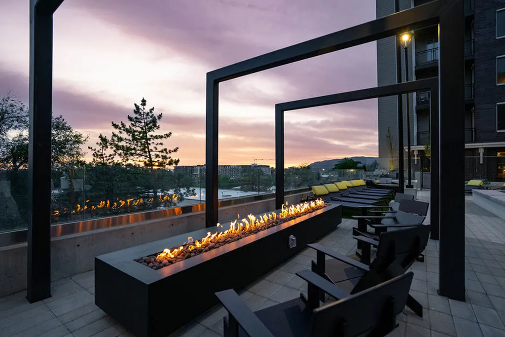 Luxurious outdoor patio with modern fire feature and stylish seating overlooking a stunning sunset view.