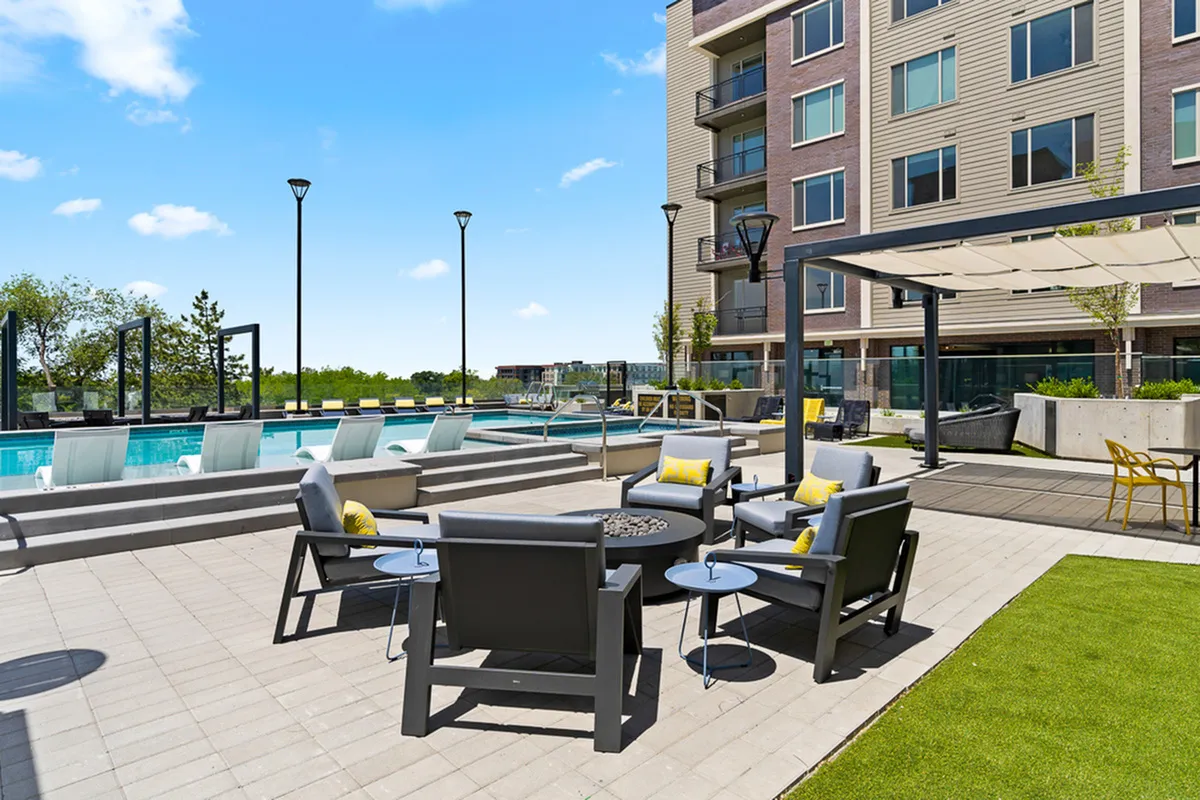 Modern apartment complex with luxurious outdoor pool and stylish seating area, perfect for relaxation and entertainment.