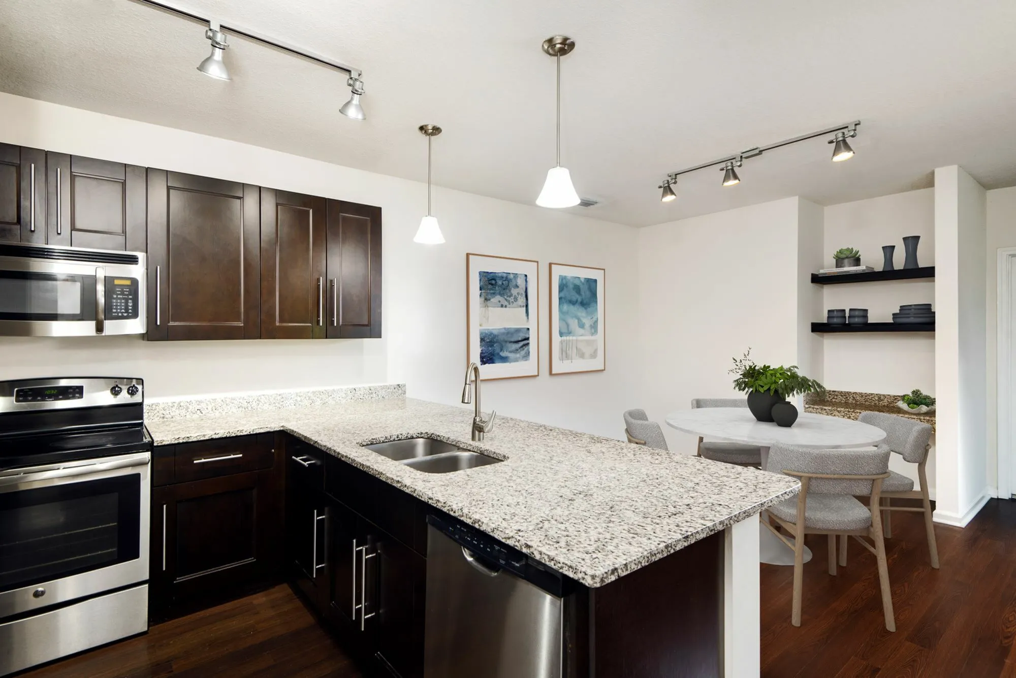 Modern kitchen with sleek dark cabinets, granite countertops, and integrated stainless steel appliances next to a chic dining area adorned with elegant artwork at The Marq Highland Park in Westchase Tampa Florida
