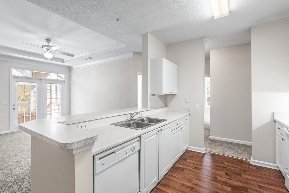 Bright and inviting kitchen at Retreat at Peachtree City Apartments with sleek countertops, modern cabinets, and an open layout leading to a spacious living area with natural light.