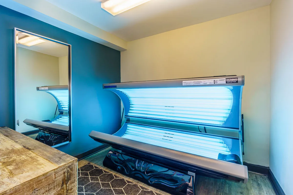 Inviting tanning room with a sleek tanning bed and modern mirror, offering a relaxing retreat.