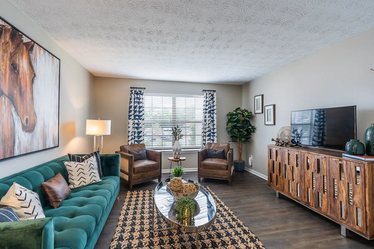Chic living room with a luxurious green sofa, elegant wood accents, and abundant natural light.