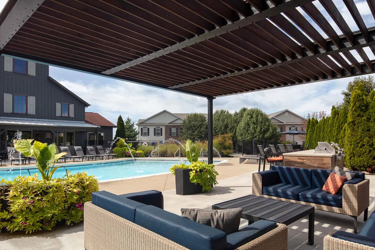 Chic outdoor lounge space featuring a sparkling pool, cozy seating, and lush greenery under a stylish pergola.
