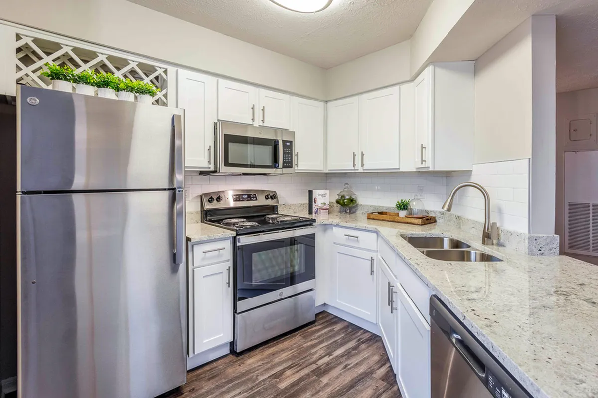 Sleek modern kitchen with stainless steel appliances, bright white cabinetry, and elegant granite countertops.