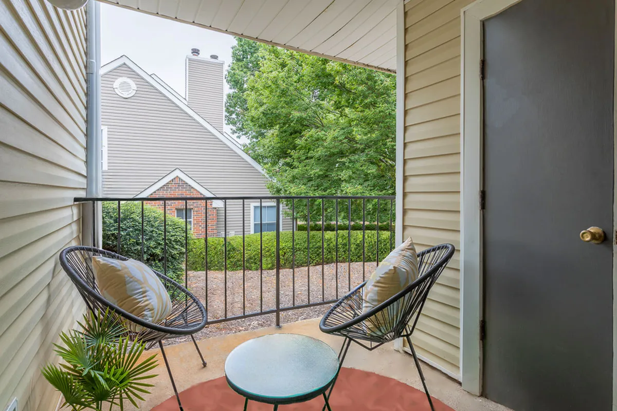 Charming apartment balcony with cozy seating, lush greenery, and a scenic view, perfect for relaxation.