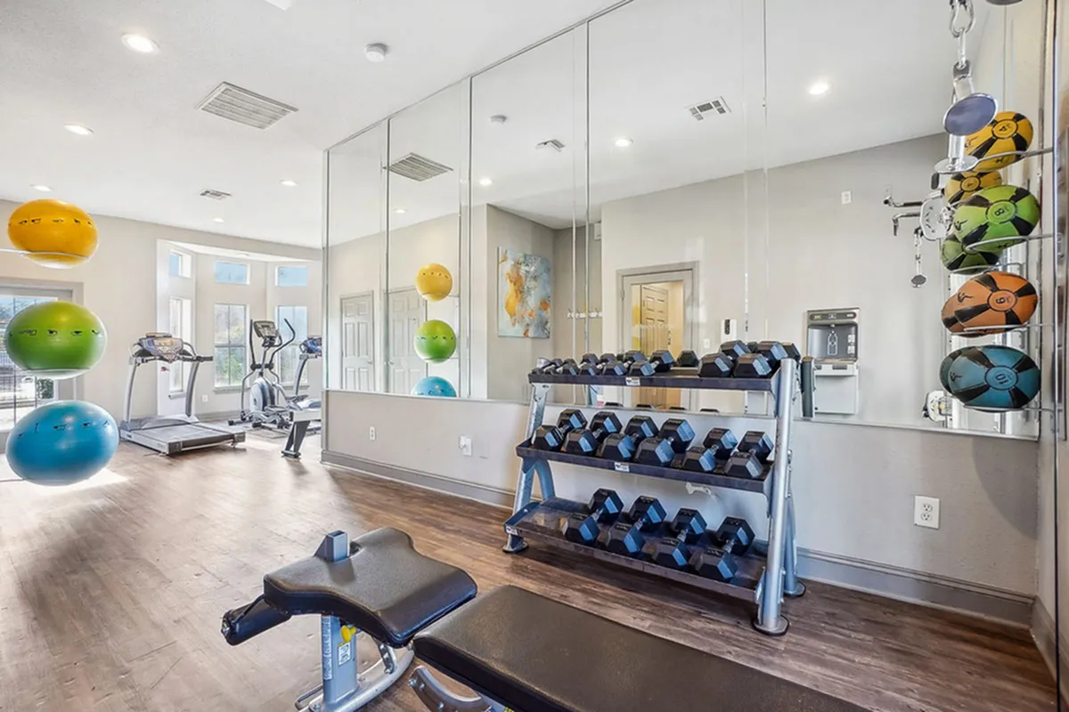 Bright, modern fitness center with mirrored walls, equipped with exercise bikes, weights, and stability balls for an invigorating workout.