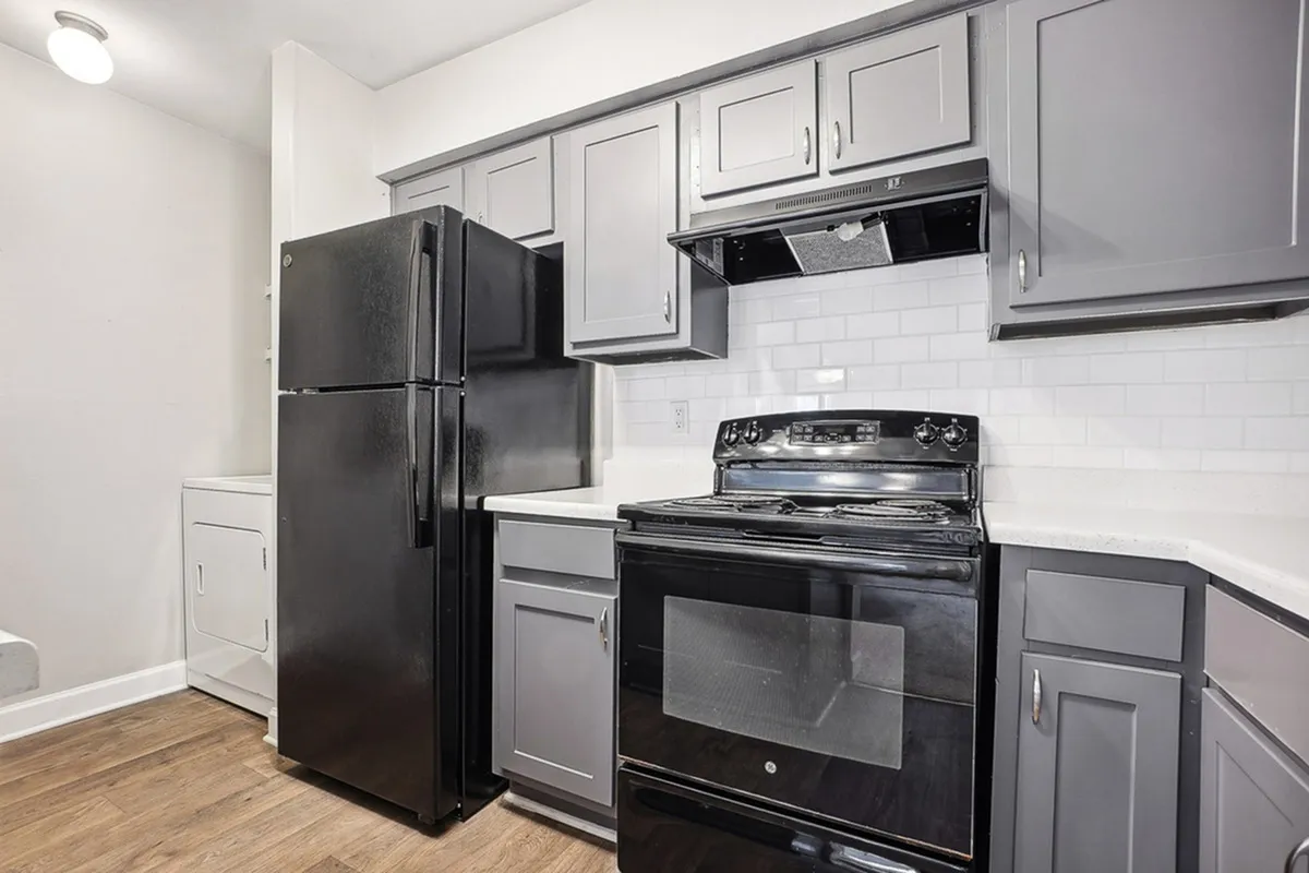 Modern kitchen with sleek grey cabinetry, black appliances, and elegant white subway tile backsplash, perfect for culinary creations.