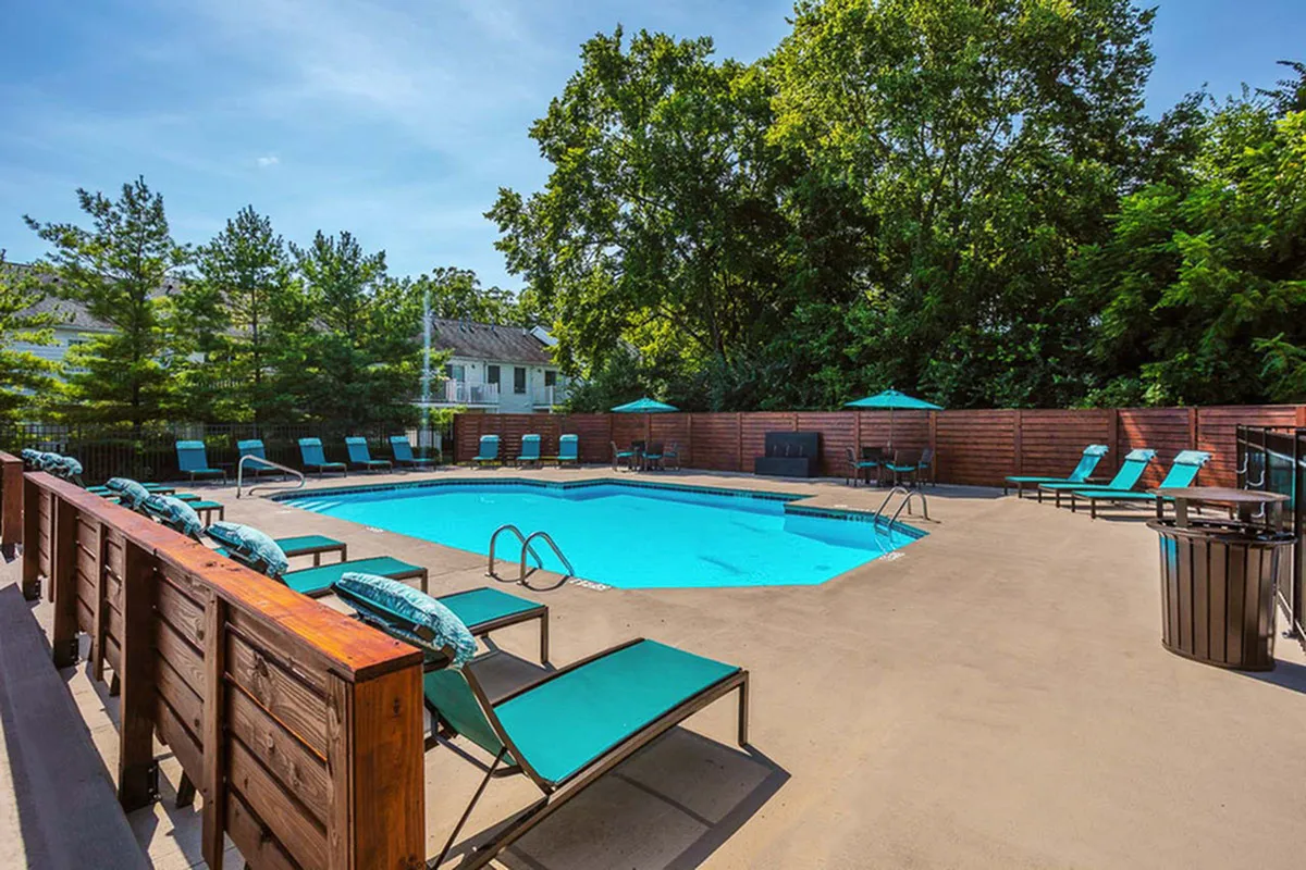 Inviting outdoor pool area surrounded by lush greenery, featuring comfortable lounge chairs and elegant poolside umbrellas.