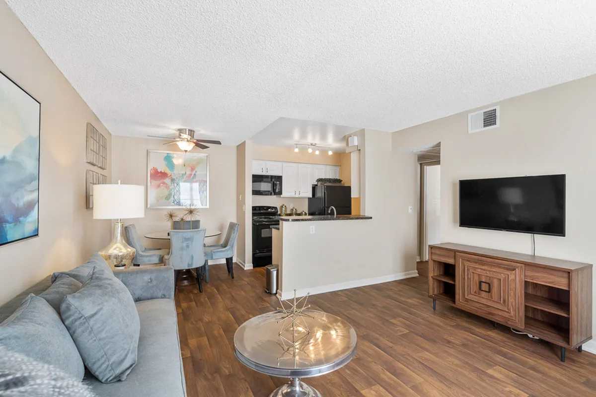 Inviting open-concept living space with modern furnishings, sleek hardwood floors, and a cozy dining area leading to a compact kitchen at Antero Apartments in Colorado Springs