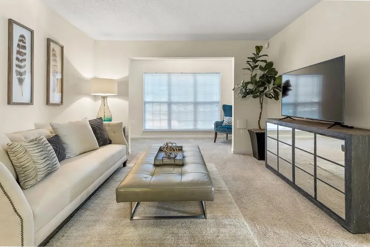 Chic living room with elegant beige sofa, stylish decor, and large window providing ample natural light.