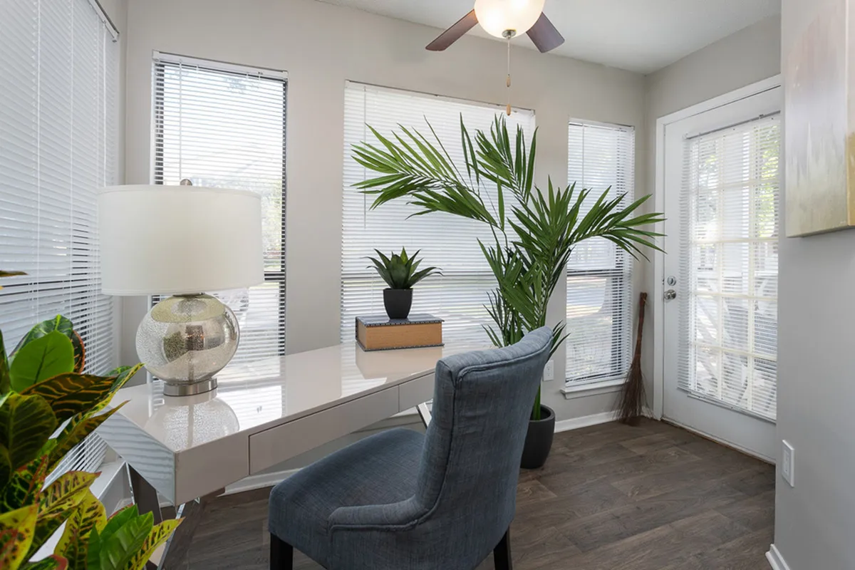 Bright and inviting home office with modern desk, elegant chair, and lush indoor plants, perfect for productivity.