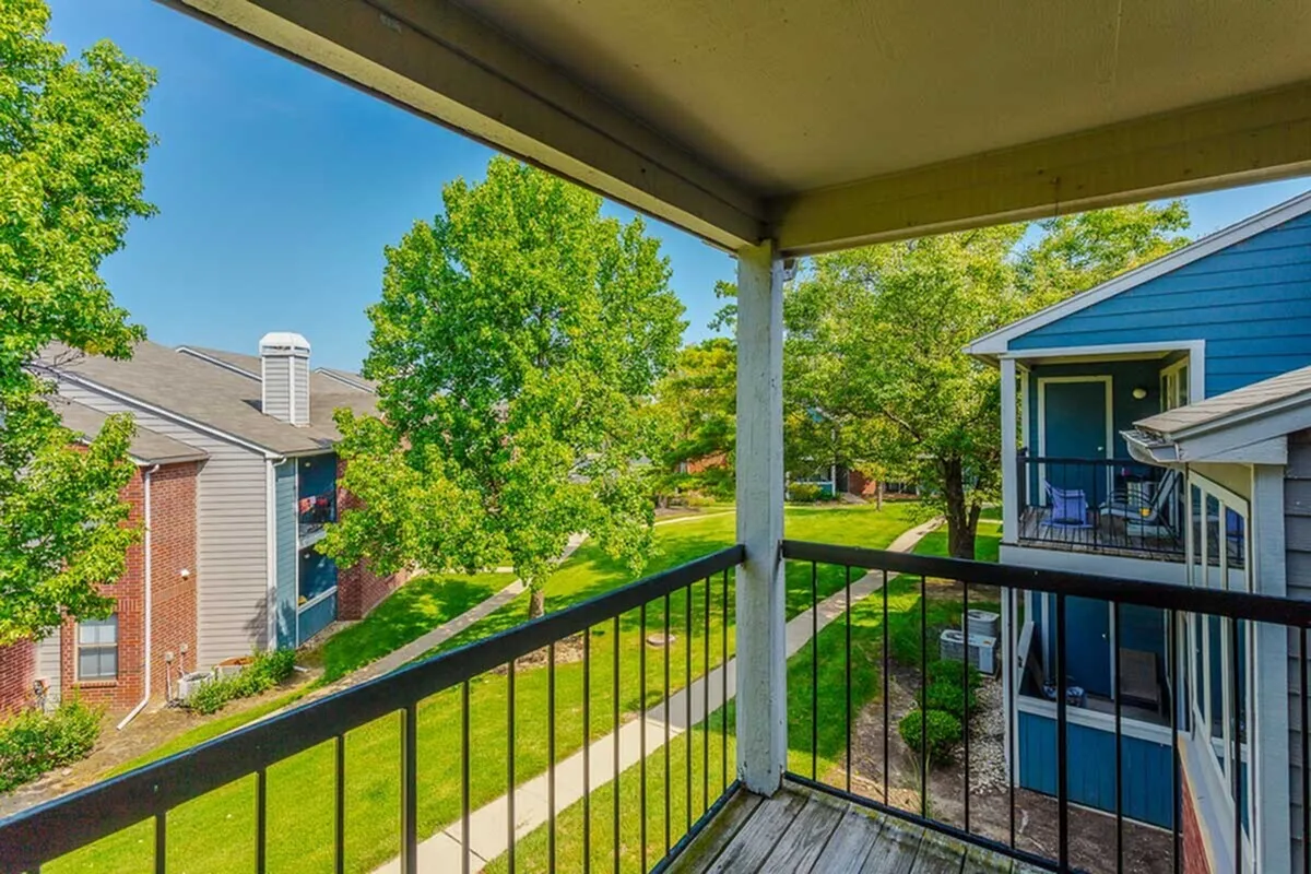 Inviting balcony view overlooking a lush, green courtyard with vibrant trees and charming apartment buildings.