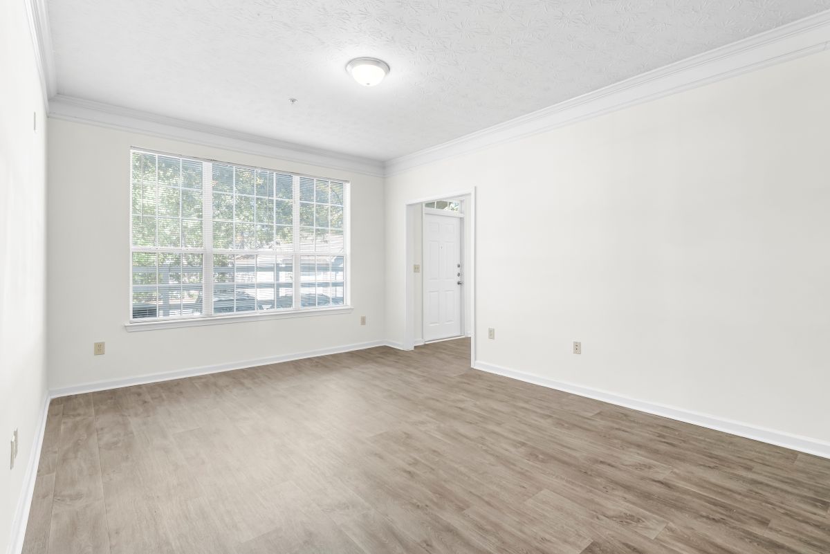Bright and airy living room with large window, elegant flooring, and modern light fixture.