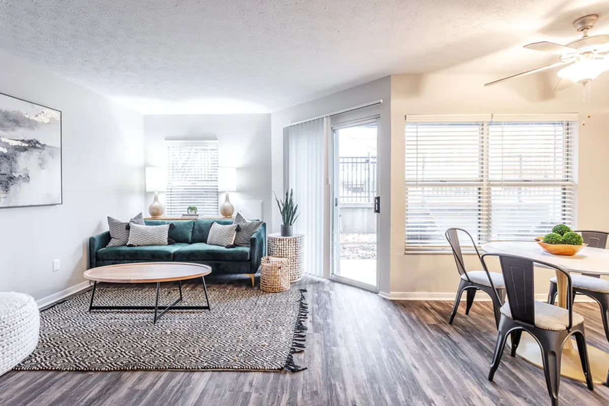 Bright living space featuring a cozy velvet sofa, modern dining area, and abundant natural light through large windows.