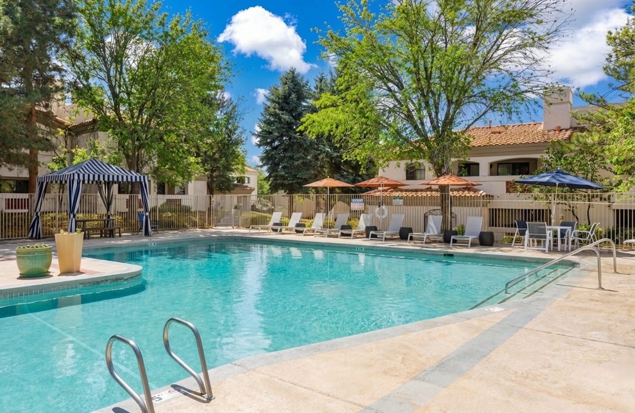 Inviting outdoor pool area with sun loungers, shaded cabanas, and lush greenery, perfect for relaxation and leisure at the pool at Pavilions Apartments.