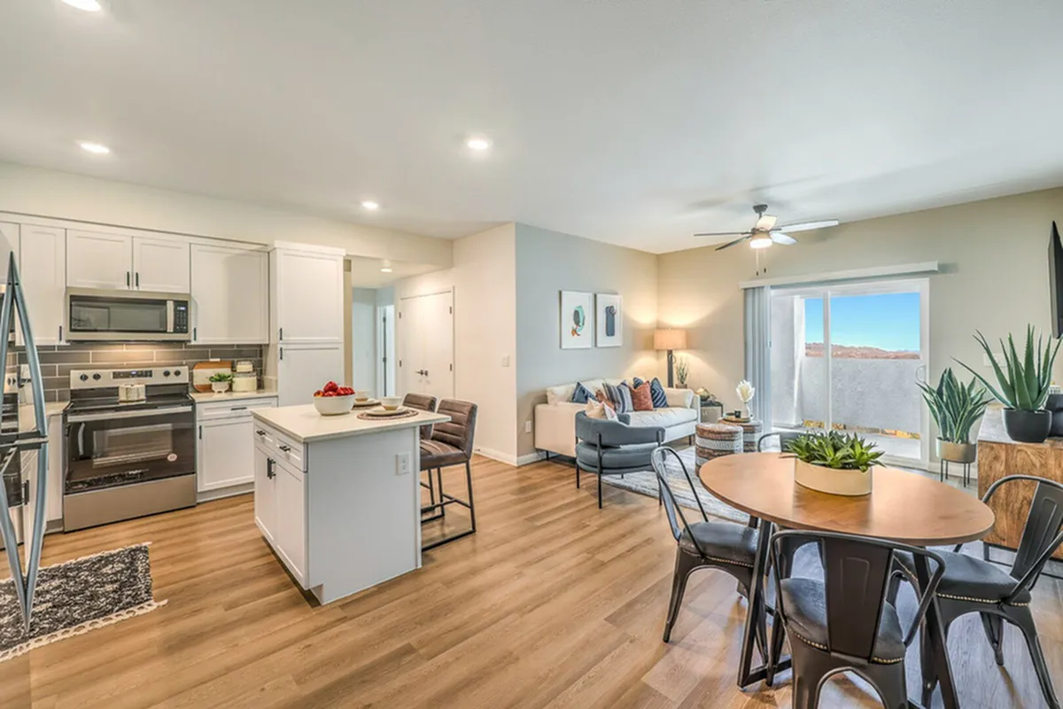 Contemporary open-concept kitchen and living area with chic dining space, modern furnishings, and natural light pouring through sliding glass doors.