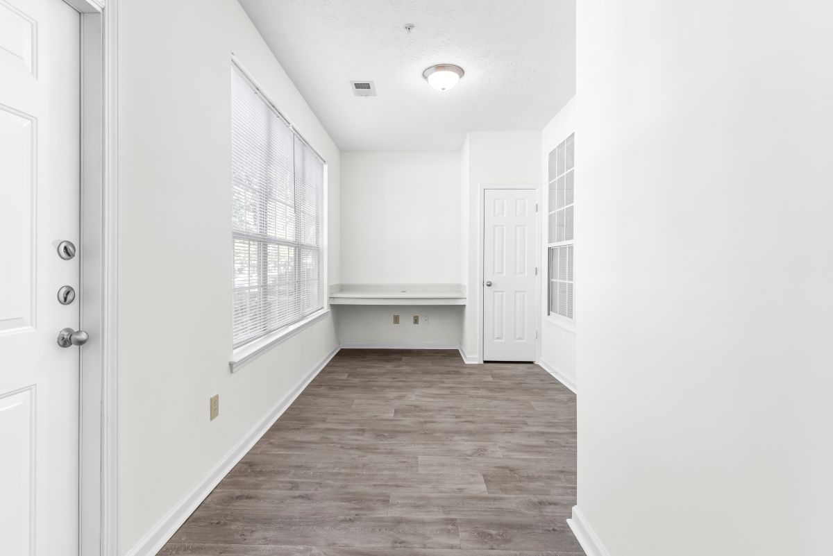 Bright entryway with large windows, wood flooring, and a built-in desk, perfect for a welcoming home office setup.