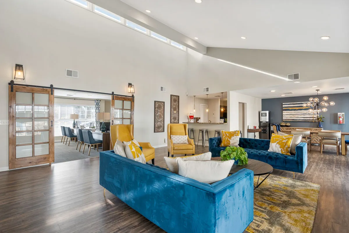 Expansive clubhouse at Antero Apartments in Colorado Springs with vibrant blue and yellow accents, modern furniture, and a stylish dining area, perfect for entertaining guests.