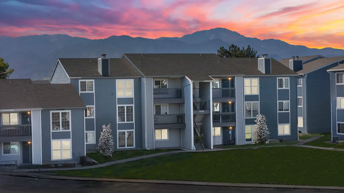 Charming modern apartment complex in Colorado Springs with stunning mountain views and vibrant sunset backdrop.