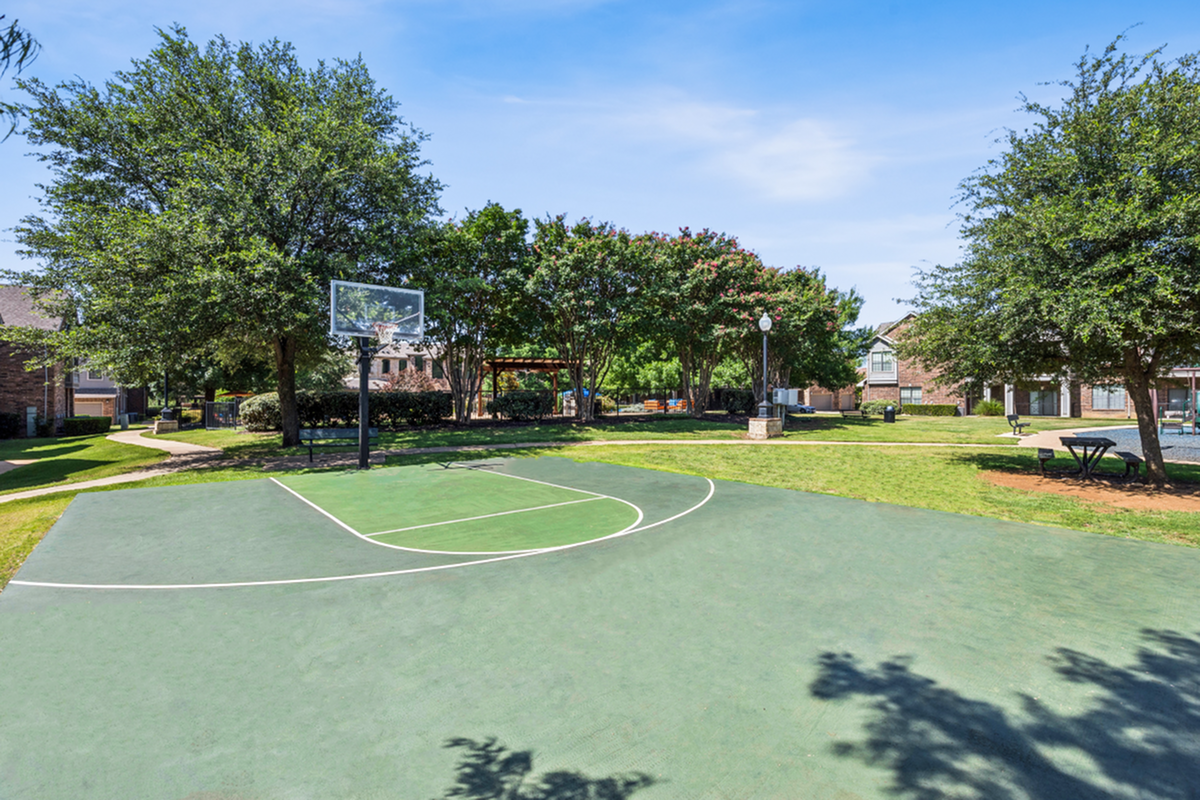 Inviting outdoor basketball court surrounded by lush greenery, offering a perfect setting for recreation in a vibrant community space.