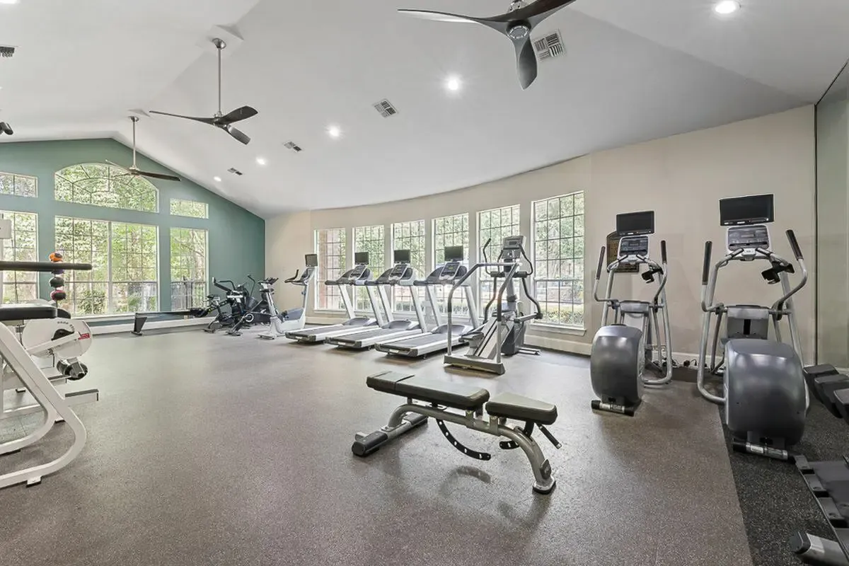View of Fitness Center with Ceiling Fan, Cardio Machines, and Mounted Flat Screen TVs at Raveneaux Apartments