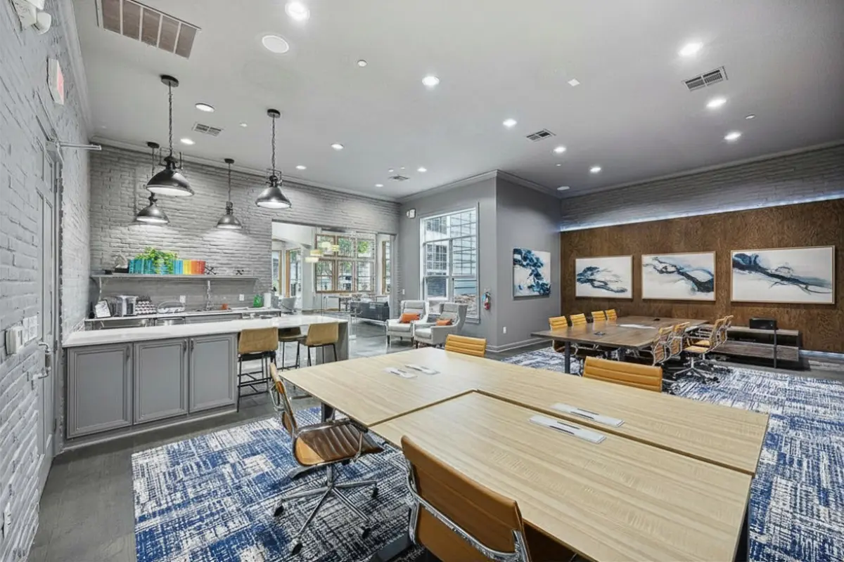 Luxurious coworking space at Cottonwood Ridgeview Apartments with modern kitchen, sleek dining area, and versatile meeting zone, enhanced by stylish lighting and vibrant decor.