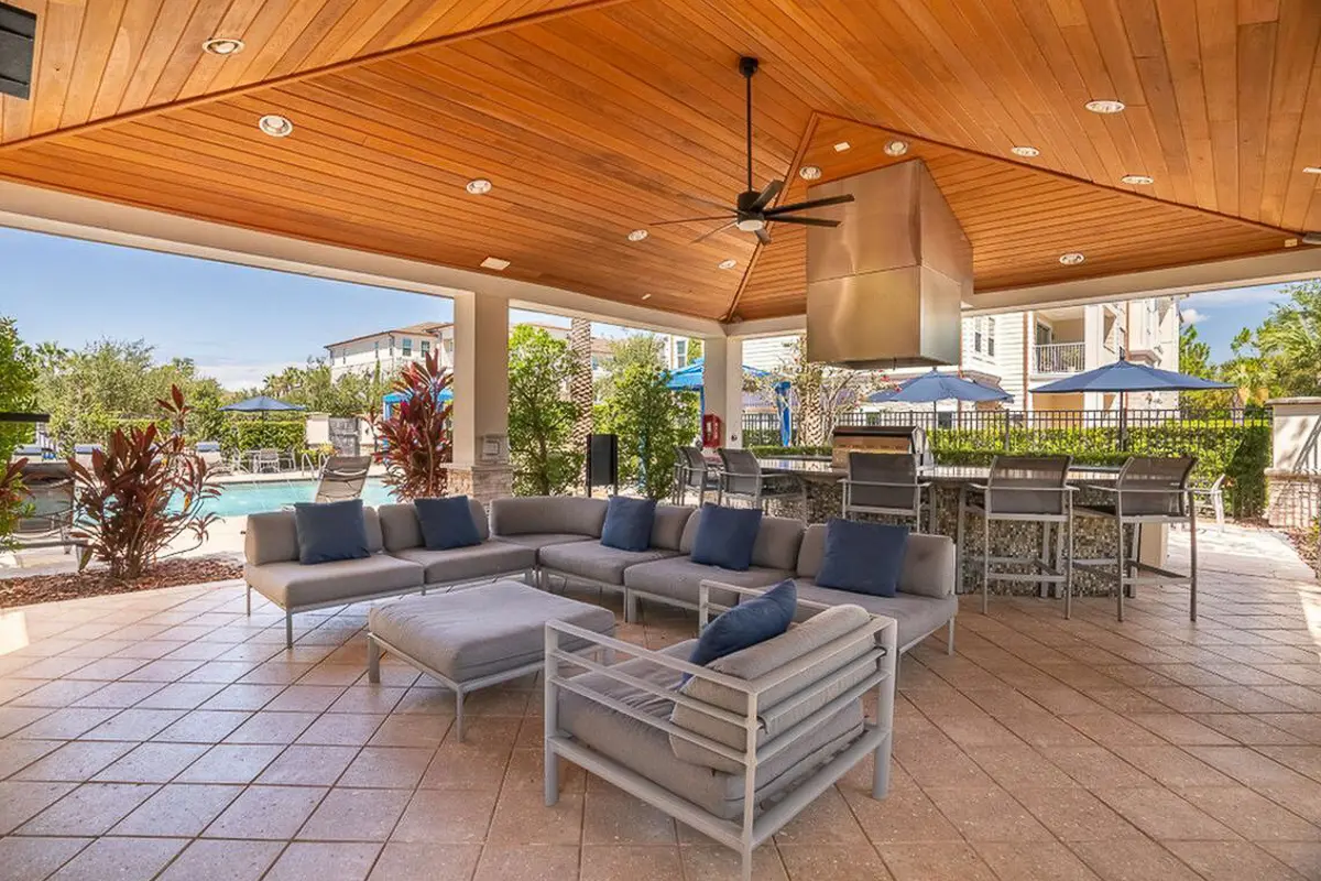 Luxurious outdoor patio with modern seating, sleek bar area, and inviting pool view, perfect for entertaining at The Marq Highland Park Apartments in Westchase Tampa