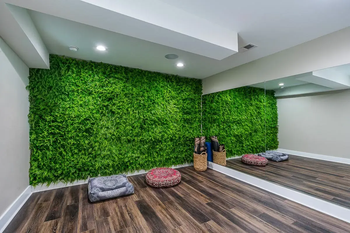 Serene home yoga studio with lush green wall, hardwood floors, and cozy meditation cushions.
