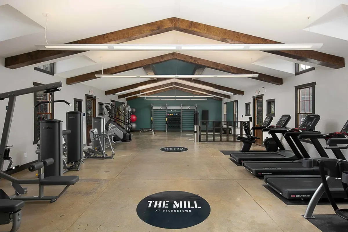 Modern fitness center with top-of-the-line equipment, vaulted ceilings, and natural light at The Mill at Georgetown.