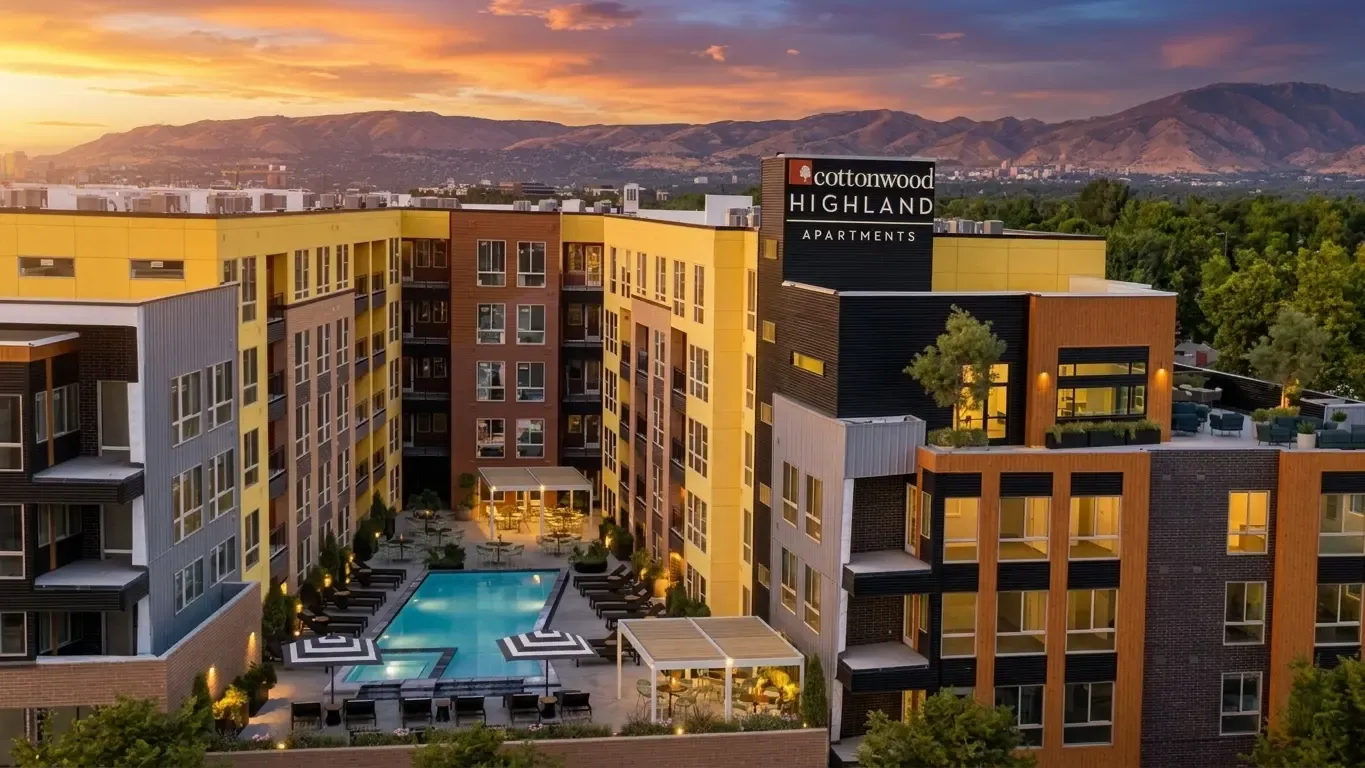 Stunning aerial view of Cottonwood Highland Apartments with a luxurious pool, modern architecture, and picturesque mountain backdrop.