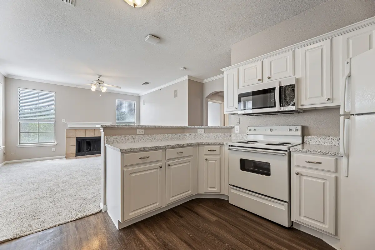 Bright kitchen with sleek granite countertops, white cabinetry, and modern appliances, perfect for culinary adventures.