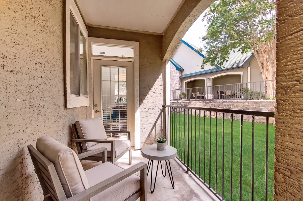 Charming patio view featuring cozy seating, vibrant cushions, and a lush garden backdrop.