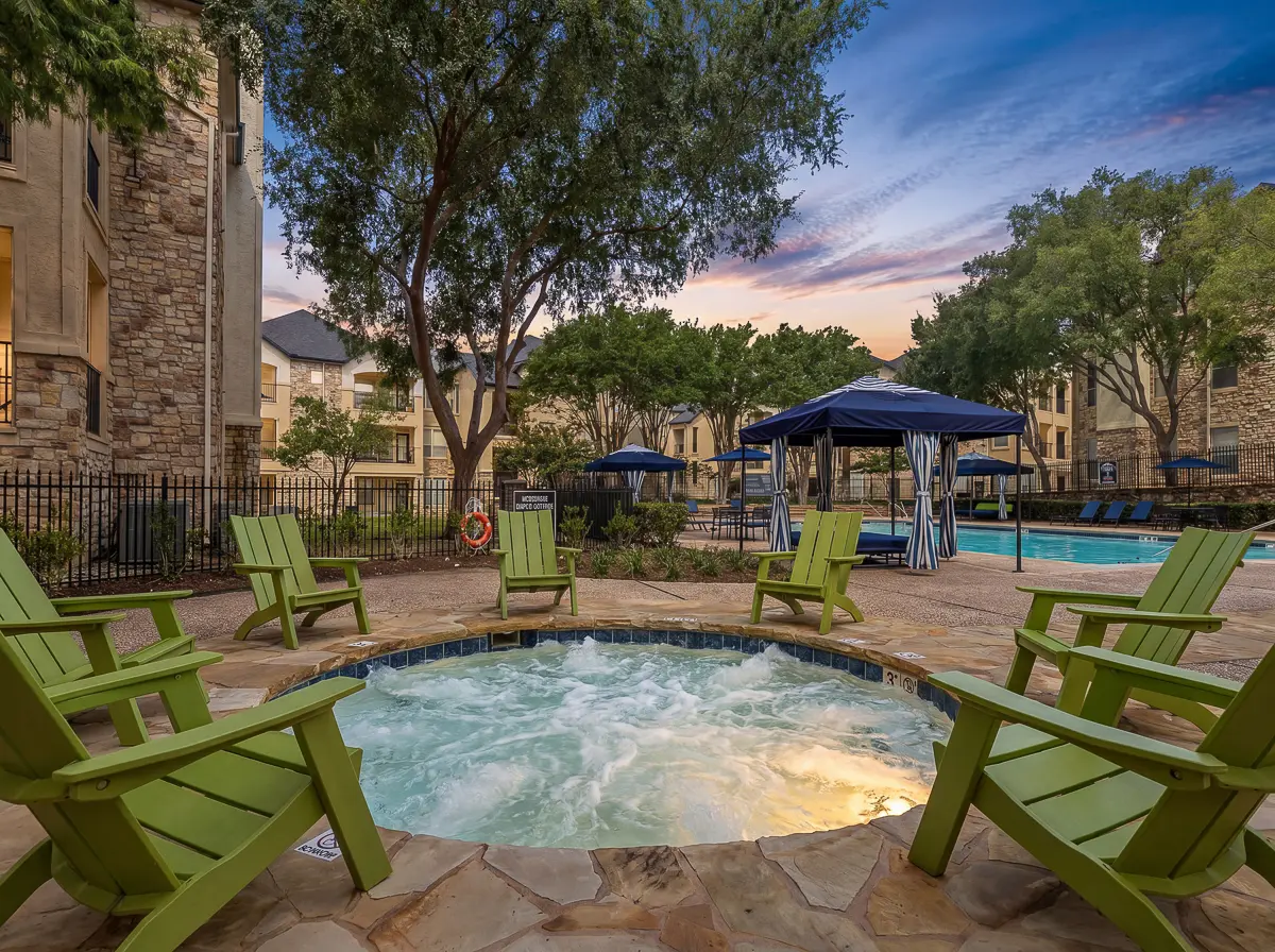 Inviting outdoor lounge with bubbling hot tub, surrounded by vibrant green chairs, under a serene evening sky, perfect for relaxation.