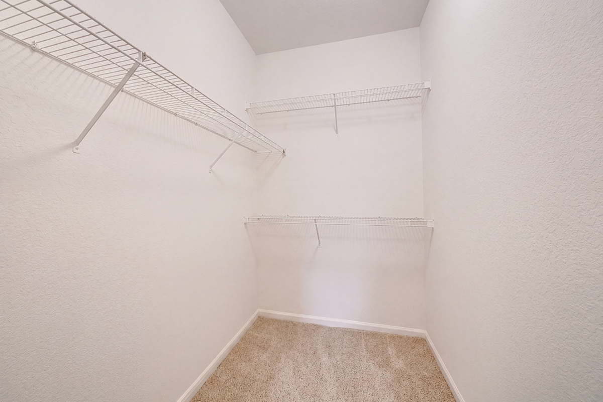 Spacious walk-in closet with wire shelving and plush carpet, offering ample storage space.
