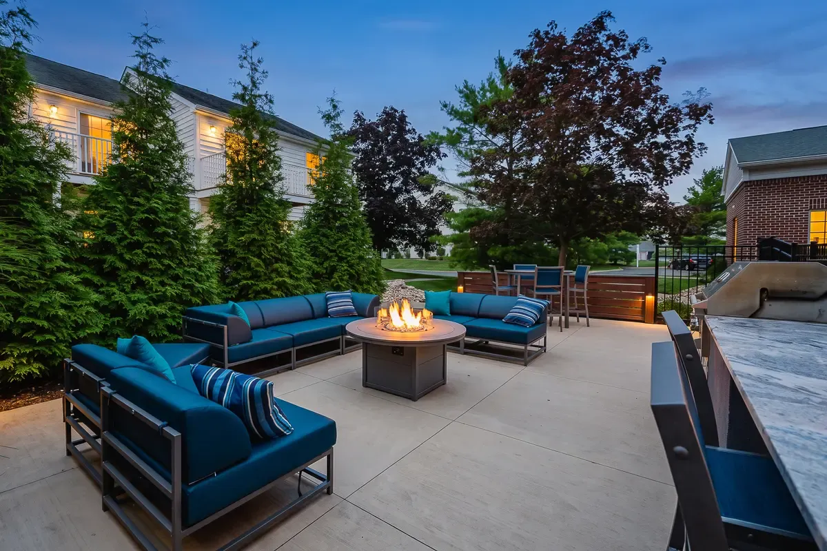 Luxurious outdoor patio featuring plush seating around a cozy fire pit, ideal for elegant evening gatherings.