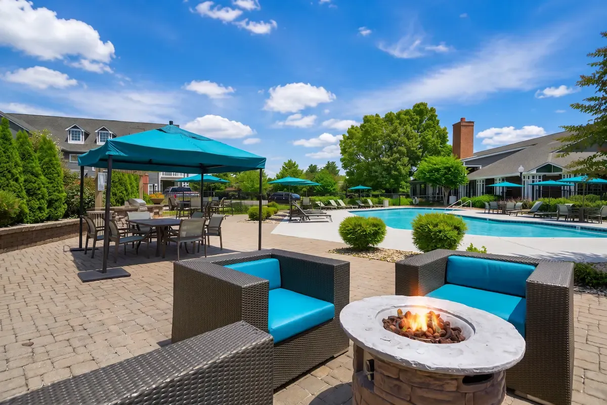 Luxurious outdoor area with cozy fire pit seating, surrounded by a beautiful pool and stylish patio furniture at sunset.