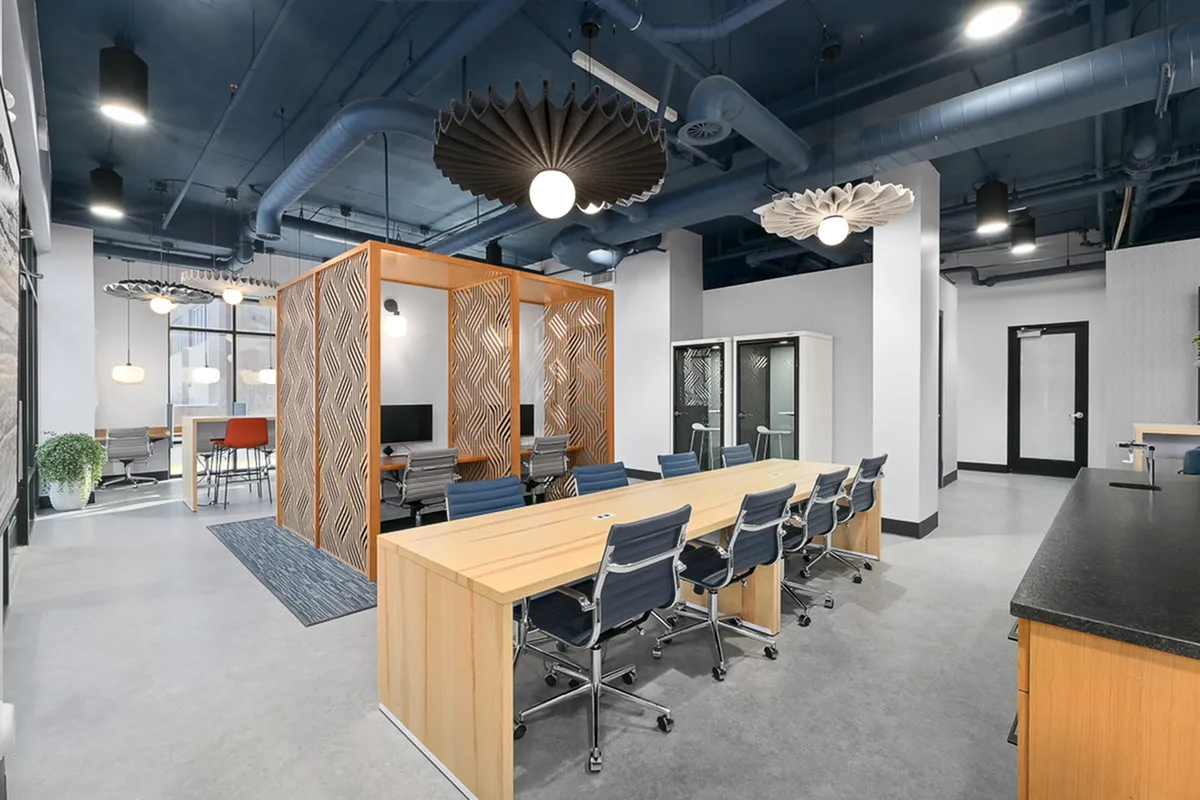 Modern co-working space featuring stylish open seating, private work booths, and eye-catching ceiling fixtures.